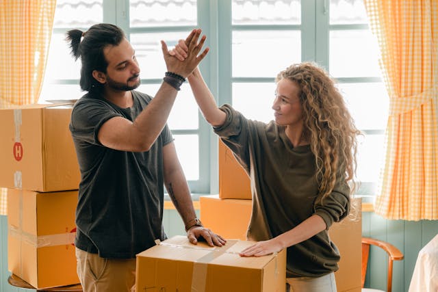 a couple high-fiving over moving boxes